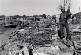 Soldier with the remains of bulldozered shacks in the squatter camp of Crossroads