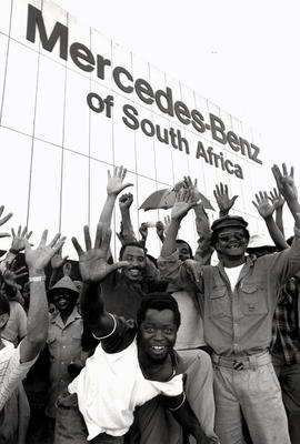 Striking Mercedes Benz South Africa workers raise 5 fingers for their demand in R5 an hour