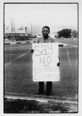 Man with "Say no to community councils" sign