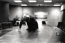 Black female night worker polishes the meeting table in the board room of an office in Johannesburg