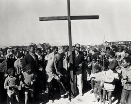 People standing around wooden cross in KTC squatter camp in Gugulethu