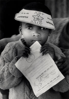 Black girl in Khayelitsha with propaganda items of the SADF aimed at the township residents