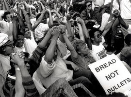People joing hands at the end of a march against police brutality under the State of Emergency
