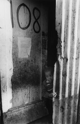 Boy of the Chicken Farm squatter camp in the door of his home - with an eviction note nailed to it