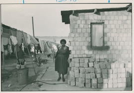 Woman standing next to her partially demolished house Alexandra