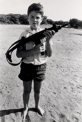 White farmer's son with the rifle of his father at the shooting range near their farm in the bord...