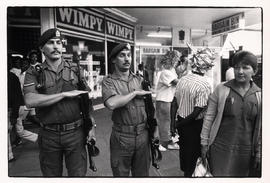 Soldiers outside a Wimpy chain shop, salute a military parade through the streets of Pietermaritz...