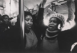Black women in a crowded commuter's train - opening prayer of an informal train church service