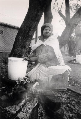 Black woman preparing food outdoors in a township in South Africa