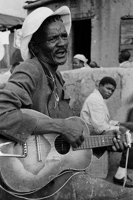 Man singing with guitar in a shebeen